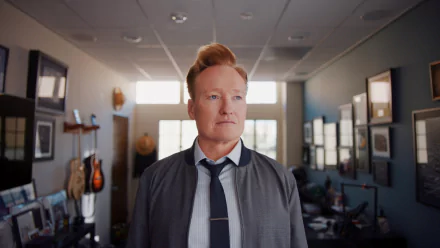 HD desktop wallpaper featuring a man with distinctive red hair and a suit, standing confidently in an office setting.