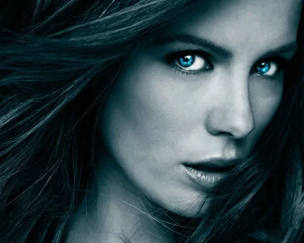 A striking HD desktop wallpaper featuring a close-up of Kate Beckinsale, showcasing her captivating gaze and flowing hair in a dramatic blue tone.