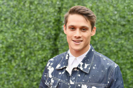 High-definition desktop wallpaper featuring a smiling man in a denim jacket against a greenery backdrop.