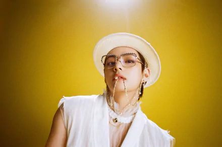 HD desktop wallpaper of V (Kim Taehyung) from BTS, a K-pop singer, wearing a white hat and glasses against a bright yellow background.