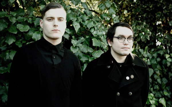 A high-definition desktop wallpaper featuring band members of Deafheaven standing against a backdrop of lush green foliage, capturing their striking style and musical essence.