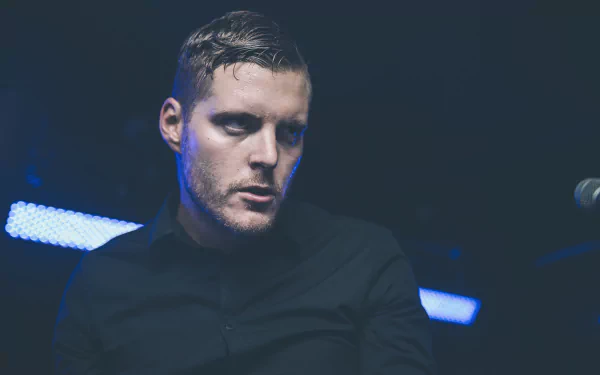 HD wallpaper featuring a member of Deafheaven performing, with a moody blue stage lighting background.
