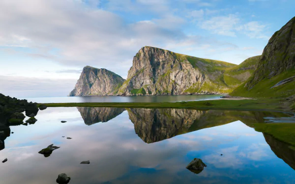 A 4K Ultra HD photo of Norway's Lofoten mountains mirrored in calm water, showcasing vivid reflection and serene natural beauty.