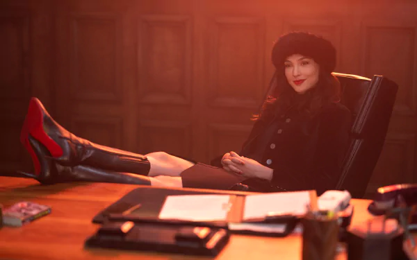 2K Quad HD desktop wallpaper: woman in fur hat and coat lounges with red heels on a desk in a wood-paneled office, cinematic lighting referencing the movie Red Notice.
