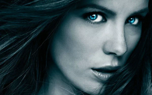 A striking HD desktop wallpaper featuring a close-up of Kate Beckinsale, showcasing her captivating gaze and flowing hair in a dramatic blue tone.