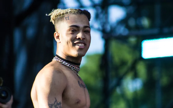 4K Ultra HD desktop wallpaper featuring a smiling XXXTentacion outdoors, capturing his distinctive style and presence in vibrant detail.