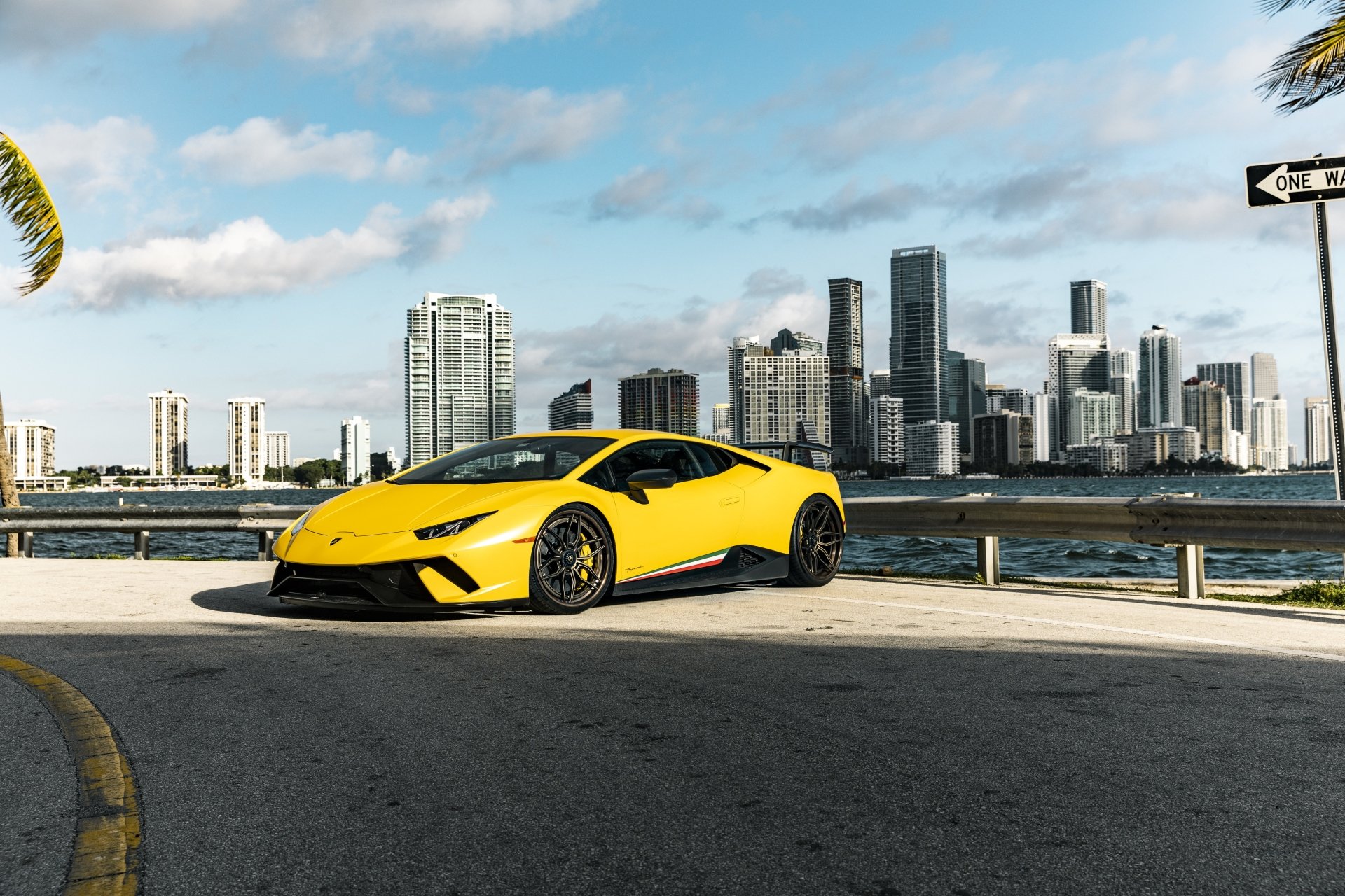 Yellow Lamborghini Huracan Performante supercar parked by the waterfront with a city skyline in the background, captured in high-resolution 4K Ultra HD.