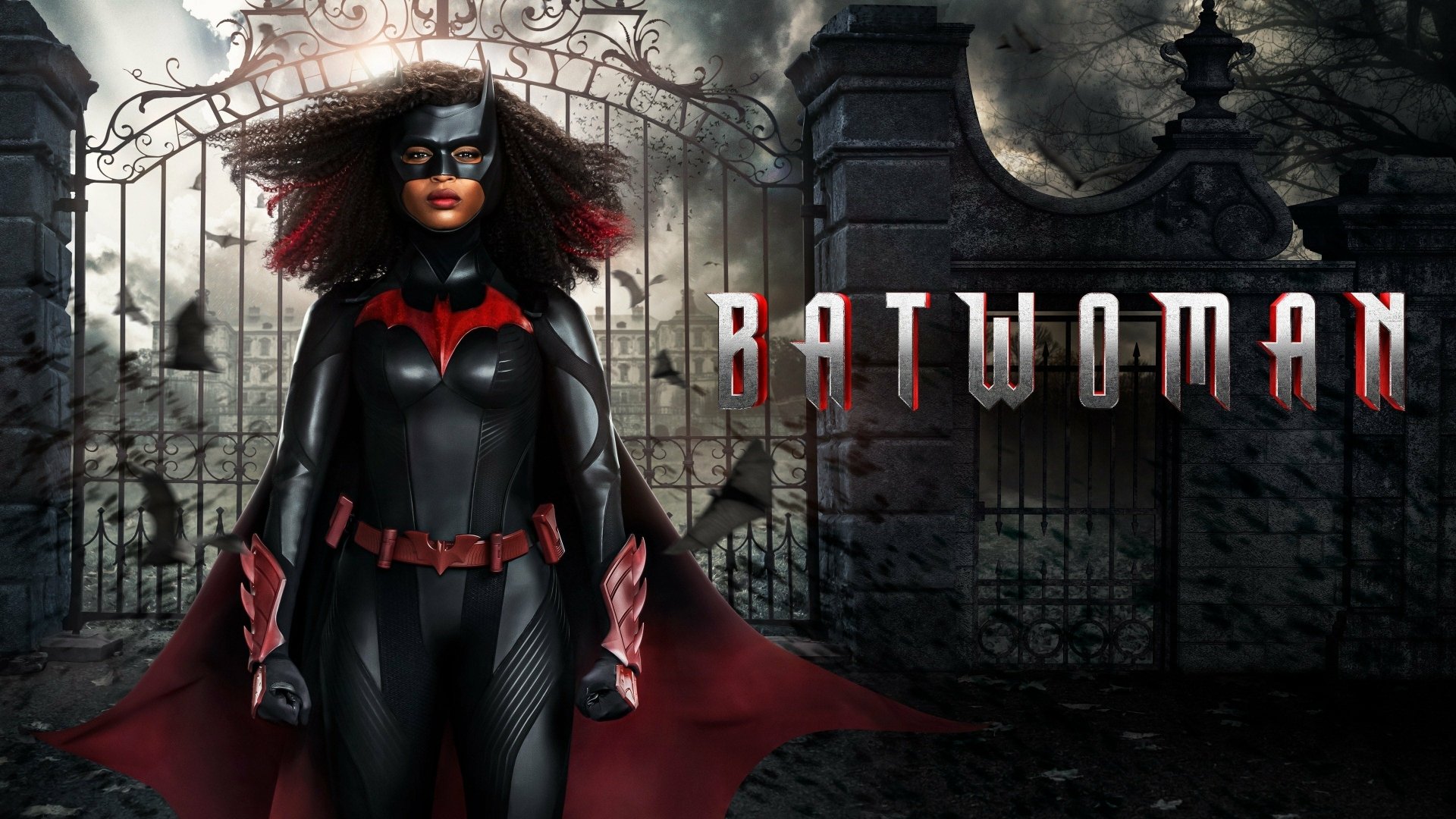TV show Batwoman in a black-and-red suit stands before a gothic iron gate under stormy skies — 4K Ultra HD PC desktop wallpaper/background.