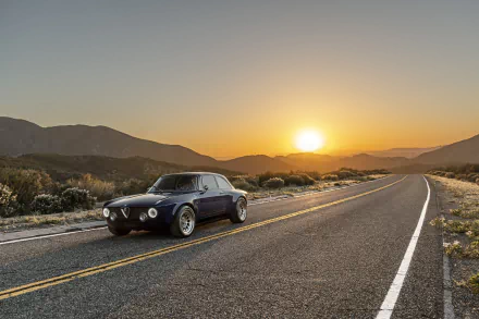Totem Automobili GT Electric vehicle on a desert highway at sunset with mountains in the distance — 8K Ultra HD PC desktop wallpaper.