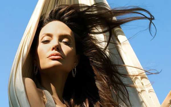 4K Ultra HD desktop wallpaper featuring a close-up of celebrity Angelina Jolie with flowing hair against a clear blue sky background.