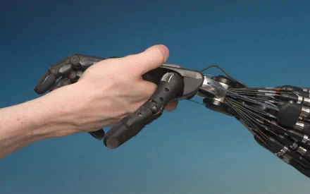 A human hand shakes a mechanical robot hand against a blue background in this HD sci-fi desktop wallpaper featuring a cyborg theme.