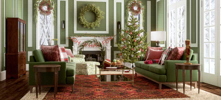 HD PC desktop wallpaper featuring a man-made room decorated for Christmas with green sofas, a Christmas tree, wreaths, and festive red and green accents.