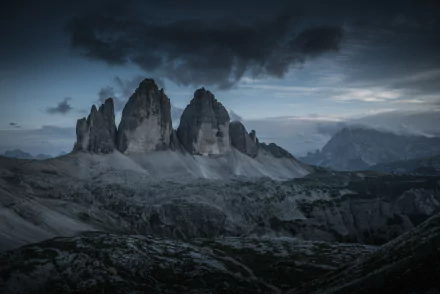 Dramatic twilight view of Tre Cime di Lavaredo peaks in the Dolomites, captured in stunning 8K Ultra HD for a breathtaking nature desktop wallpaper.