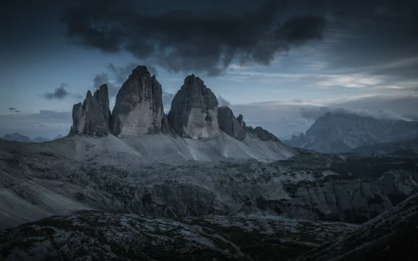 Dramatic twilight view of Tre Cime di Lavaredo peaks in the Dolomites, captured in stunning 8K Ultra HD for a breathtaking nature desktop wallpaper.