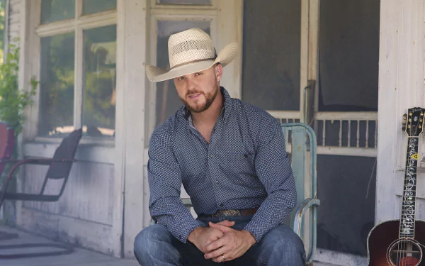 HD desktop wallpaper featuring a man in a cowboy hat sitting on a porch beside a guitar.