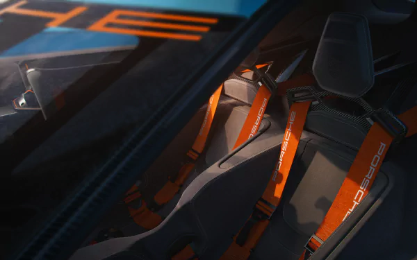 A close-up view of the interior of the Porsche Vision 908, featuring orange racing harnesses and sleek design elements, showcased as an HD desktop wallpaper.