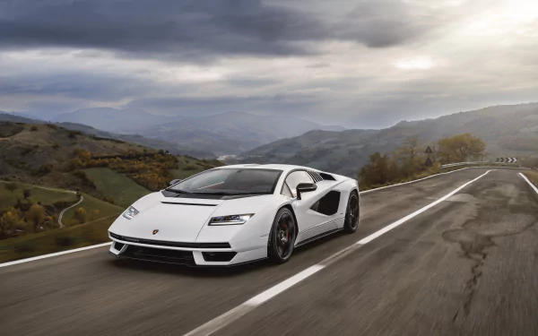 White Lamborghini Countach LPI 800-4 supercar vehicle speeding on a winding mountain road under a dramatic sky — 8K Ultra HD PC desktop wallpaper background.