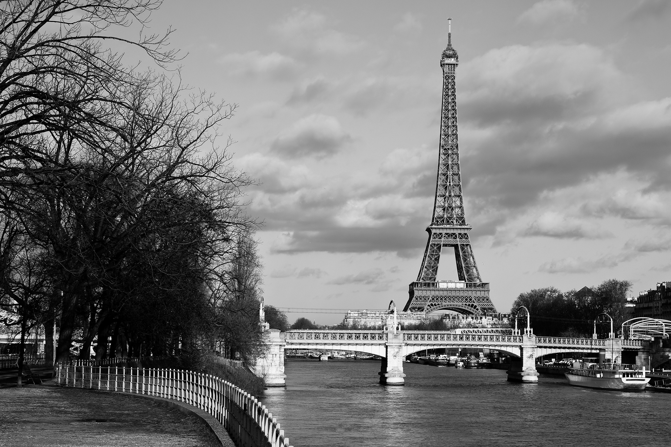 Monochrome view of the iconic Eiffel Tower rising above an elegant bridge in Paris, France.