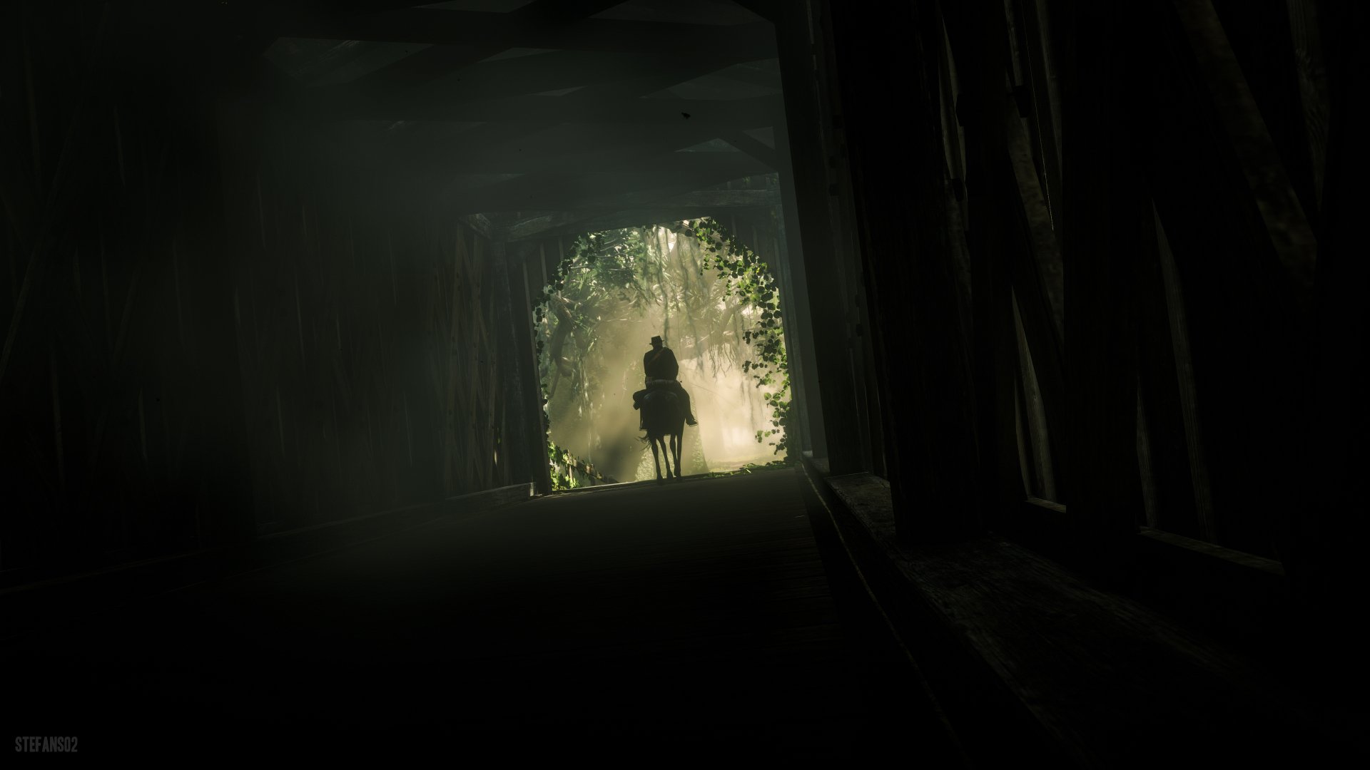 A silhouetted rider on horseback enters a sunlit forest tunnel, captured in stunning 4K Ultra HD from the video game Red Dead Redemption 2.
