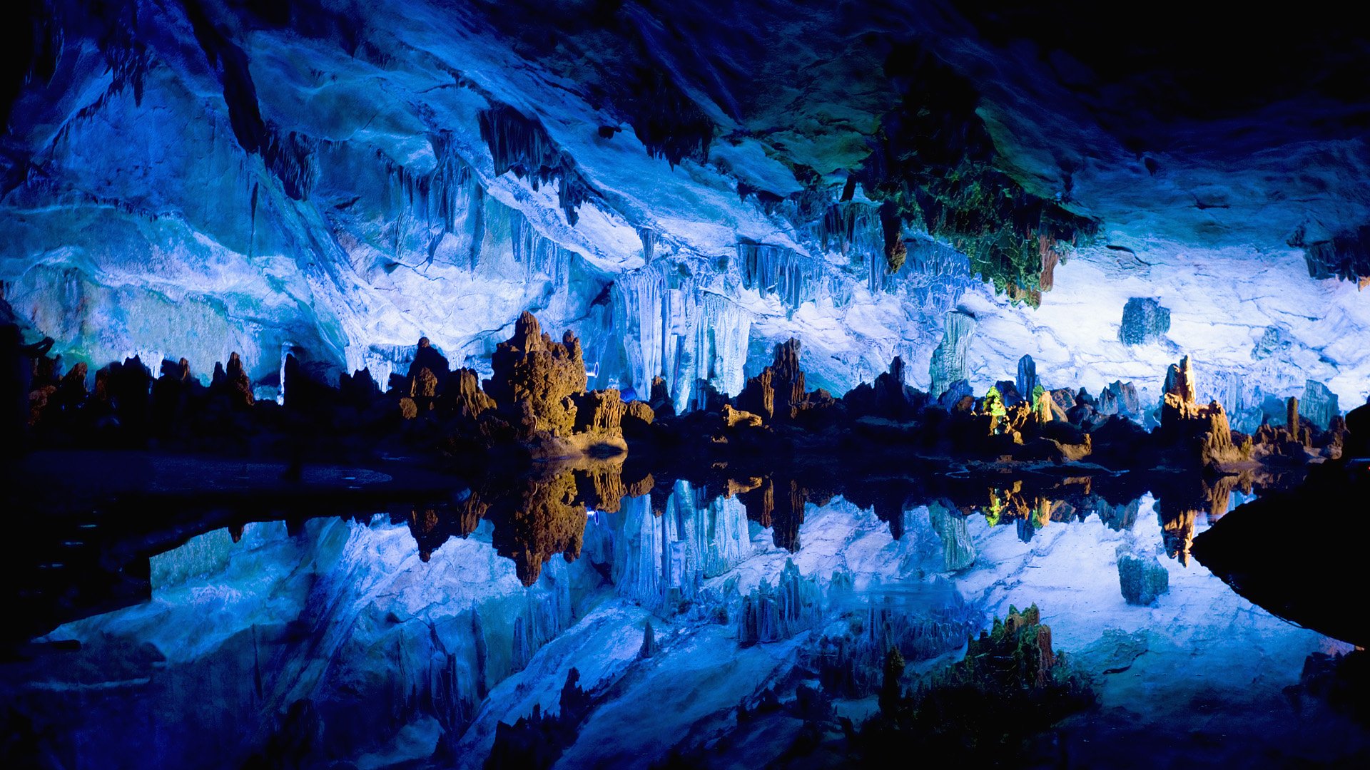 HD PC desktop wallpaper showcasing a stunning natural mountain cave with icy blue formations reflected in calm water, creating a serene and mystical atmosphere.