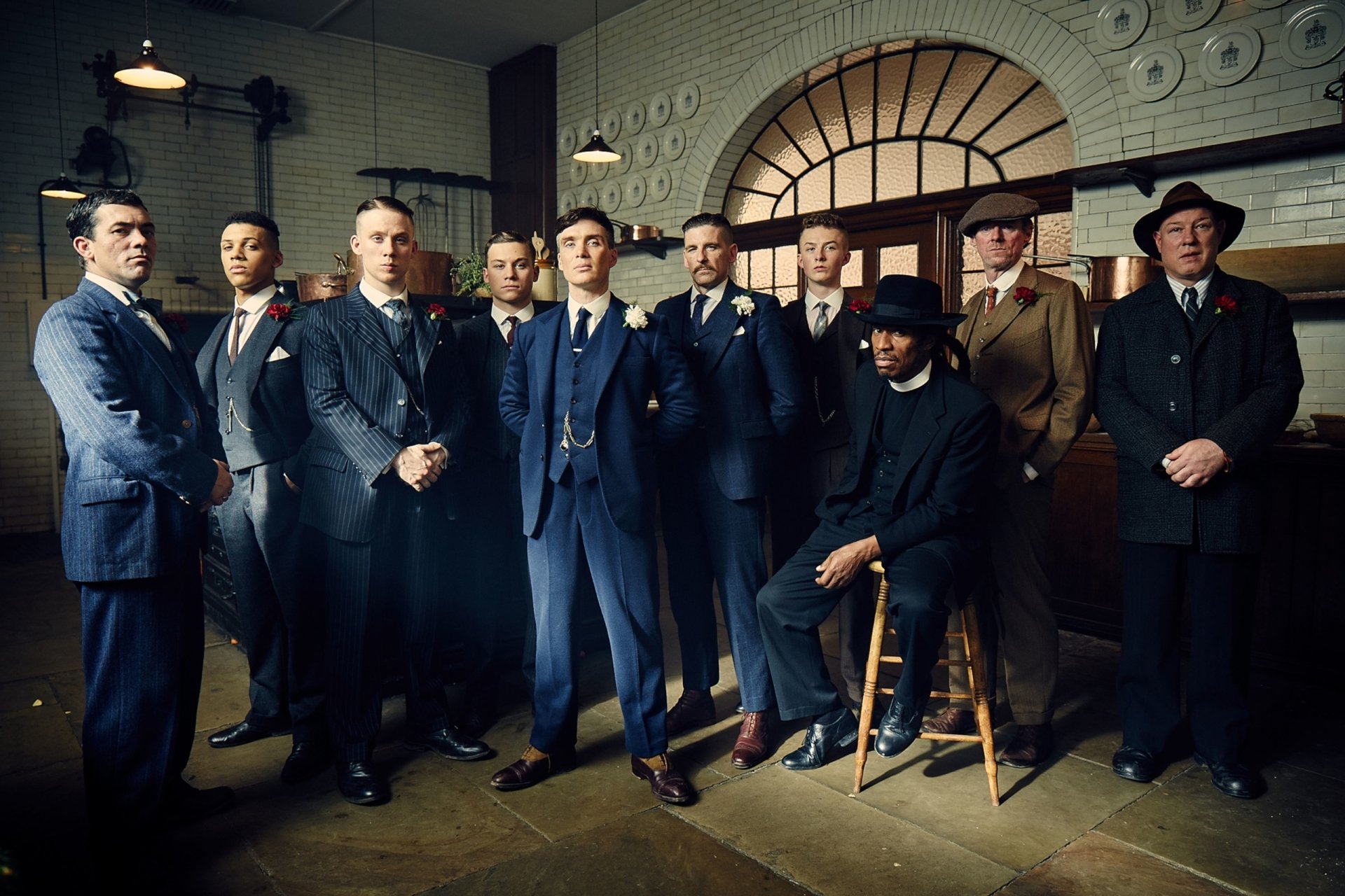 Peaky Blinders TV show group portrait: men in 1920s suits and caps in a moody industrial room — 2K Quad HD PC desktop wallpaper and background.