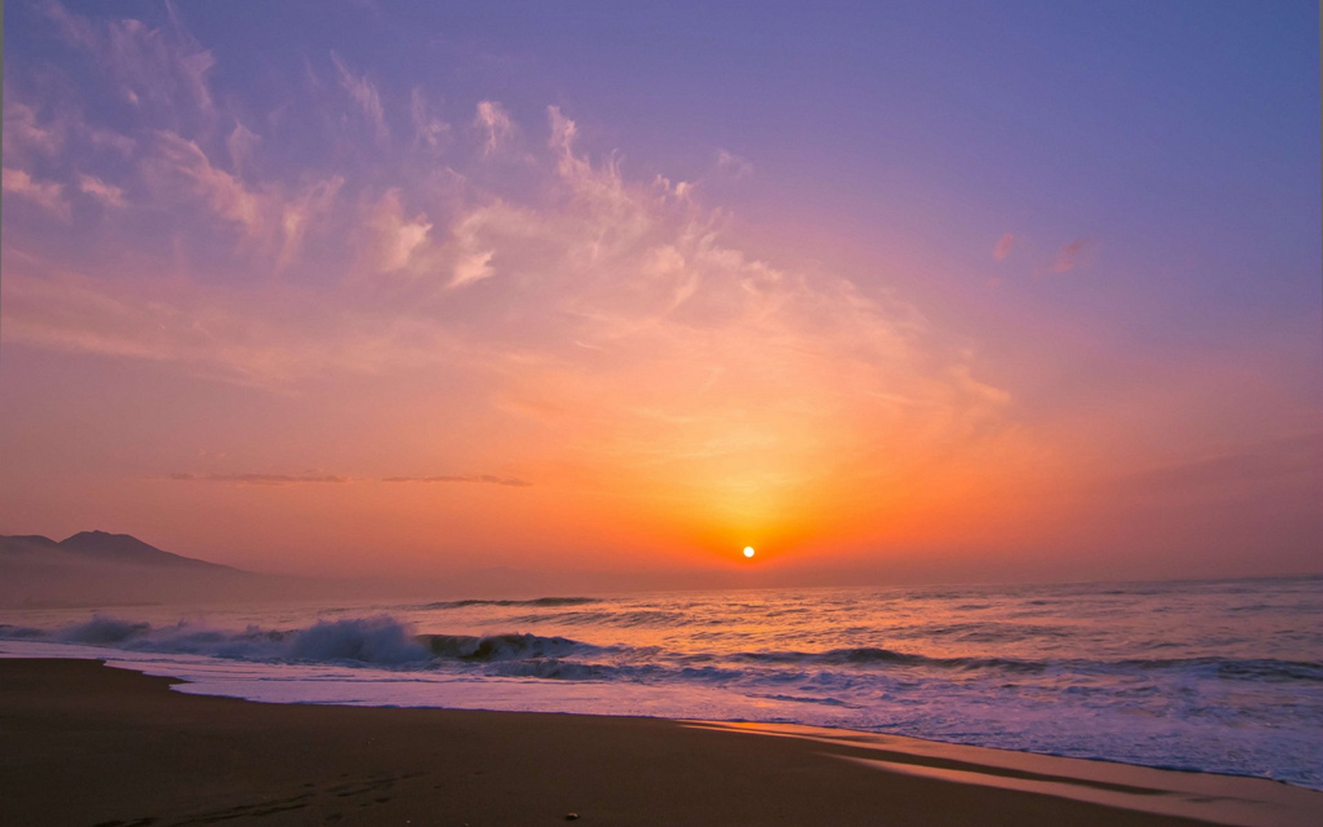 HD PC desktop wallpaper showing a serene beach at sunset with waves gently washing ashore under a vibrant sky.