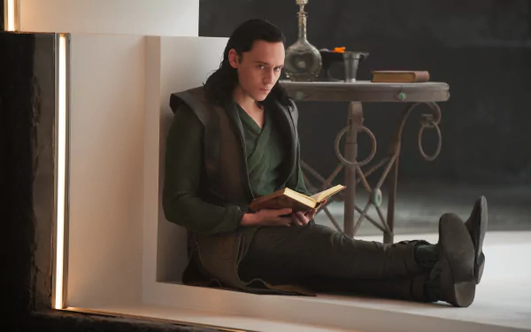 Loki from Thor: The Dark World sits against a ledge reading a book in a moody movie still, presented as a 5K Ultra HD PC desktop wallpaper and background.