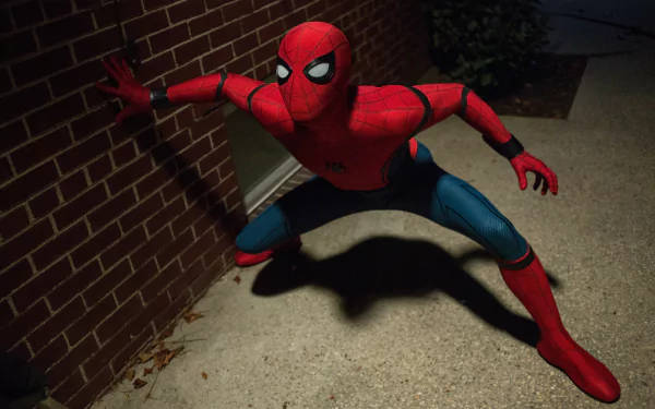 HD desktop wallpaper of Spider-Man in action from the movie Spider-Man: Homecoming. Spider-Man is in a crouched position, ready for action, against a brick wall at night.