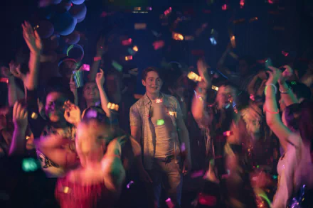 Heartstopper (TV show) scene: teen smiling amid a dancing crowd, confetti and neon club lights — 4K Ultra HD PC desktop wallpaper/background.