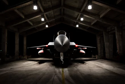 A McDonnell Douglas F-15 Eagle military jet sits inside a dimly lit hangar, captured in a striking 4K Ultra HD desktop wallpaper.