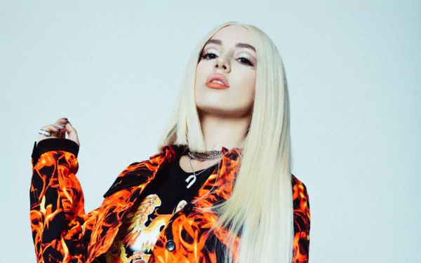HD PC desktop wallpaper: blonde pop singer in a fiery flame-print jacket and bold makeup, music-themed portrait for a striking background.