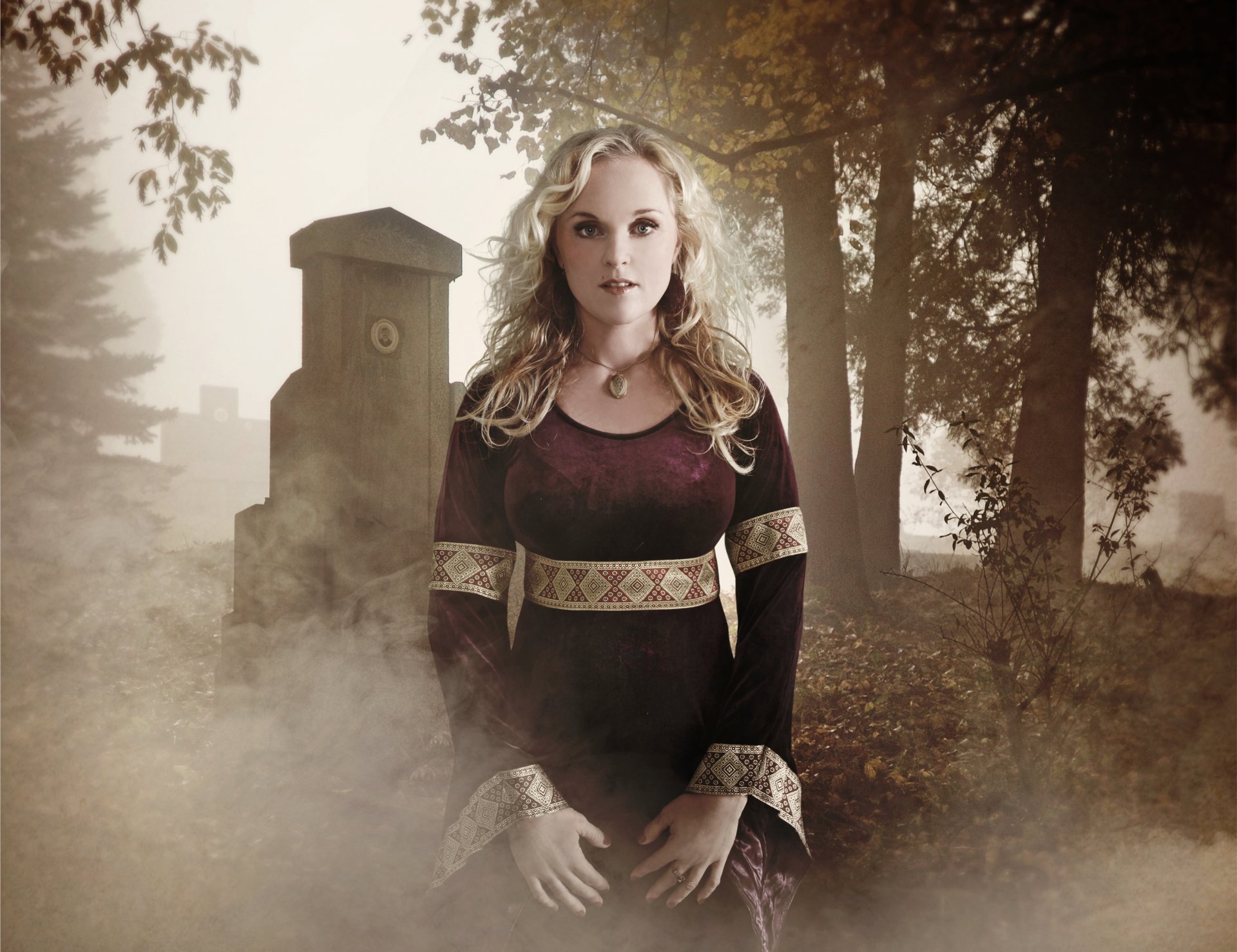 HD PC desktop wallpaper featuring Liv Kristine standing in a misty, forested area with a tombstone in the background, evoking a music-themed, atmospheric scene.