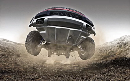 HD PC desktop wallpaper featuring a Ford Raptor vehicle captured mid-jump over rugged terrain, showcasing its off-road capability and powerful design.