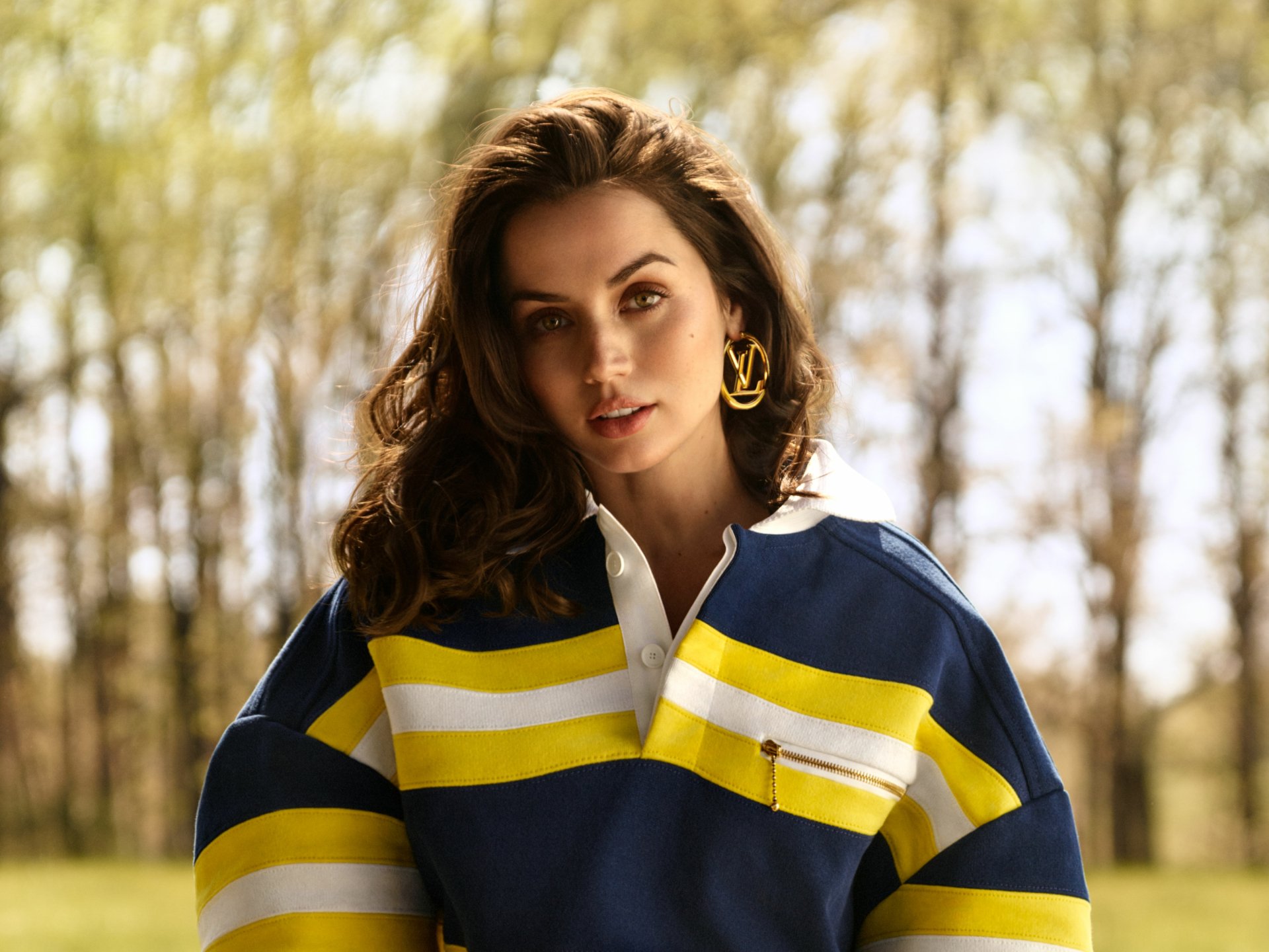 HD PC desktop wallpaper featuring celebrity Ana de Armas in a blue, yellow, and white striped top, standing outdoors with a softly blurred natural background.