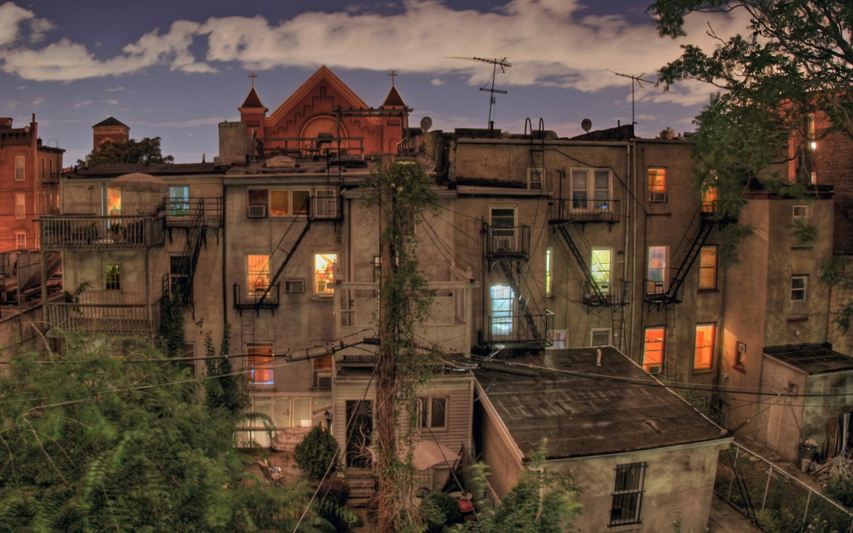 HD desktop wallpaper of a man-made building at night, showcasing a rustic, multi-story structure with lit windows, and a dramatic sky backdrop, creating a serene and atmospheric cityscape.