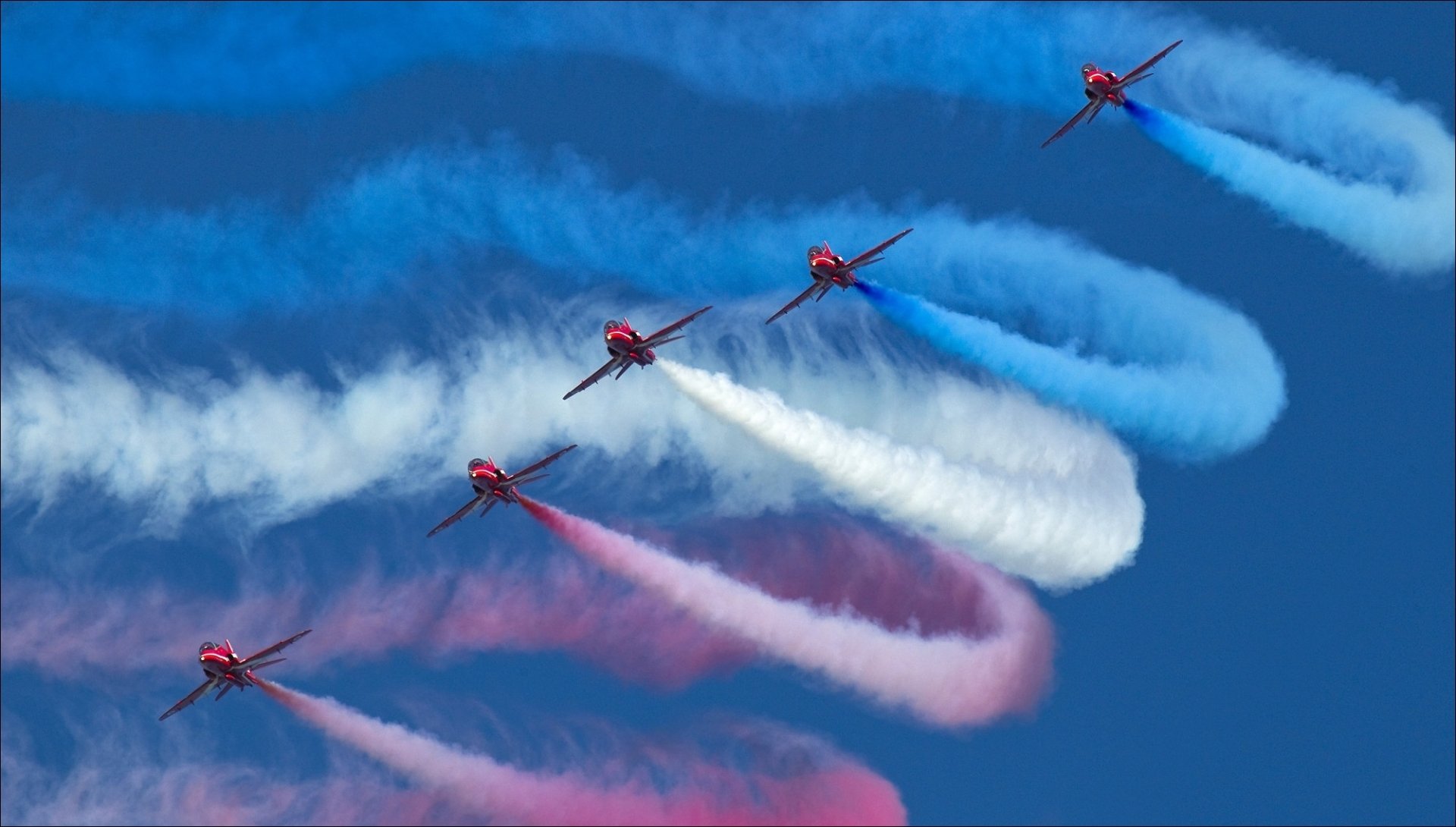 HD PC desktop wallpaper featuring a military air show with six red jets leaving colorful red, white, and blue smoke trails against a vibrant blue sky.