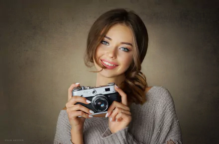 HD PC desktop wallpaper: smiling woman model in a cozy sweater holding a vintage camera against a warm, textured backdrop.