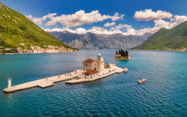 A serene 4K Ultra HD view of the religious church on a small island in Kotor Bay, Montenegro, surrounded by blue waters and mountainous landscape.