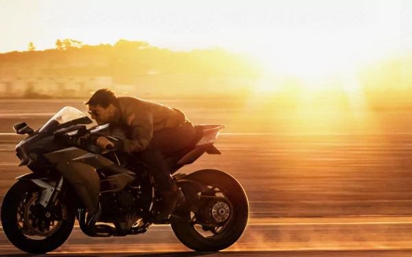 HD PC desktop wallpaper featuring a scene from the movie Top Gun: Maverick with a rider speeding on a motorcycle at sunset.