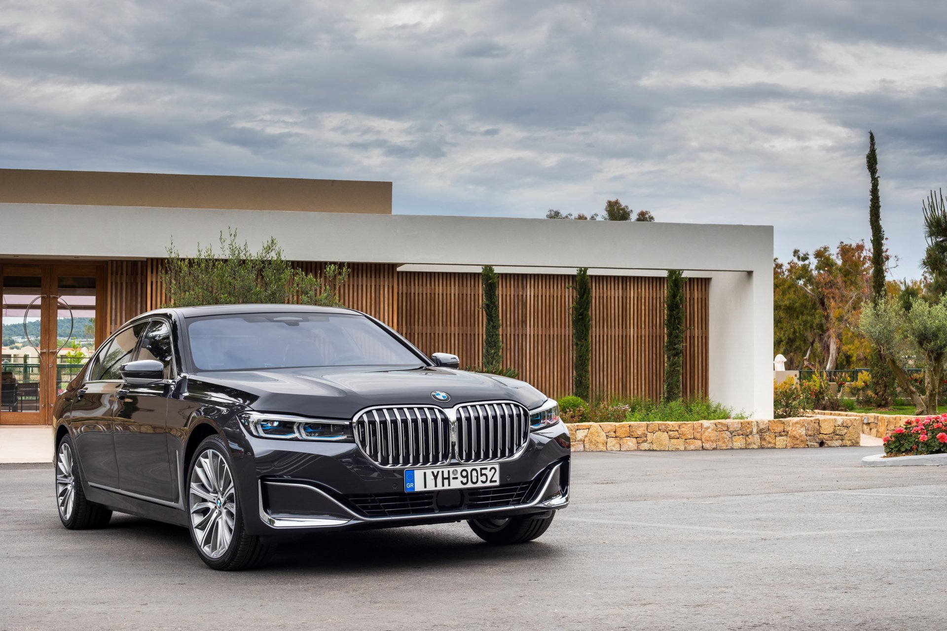 Vehicle, BMW 7 Series sedan parked in front of a modern house under a cloudy sky, 2K Quad HD PC desktop wallpaper/background.