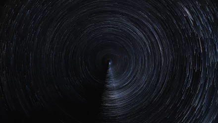 A mesmerizing HD desktop wallpaper showcases a circular star trail pattern against a dark sky, capturing the enchanting beauty of nature at night.