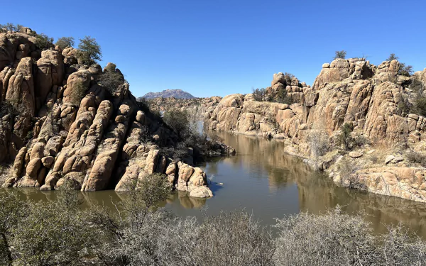 4K Ultra HD desktop wallpaper featuring a tranquil river winding through rugged rocky cliffs under a clear blue sky in a natural landscape.