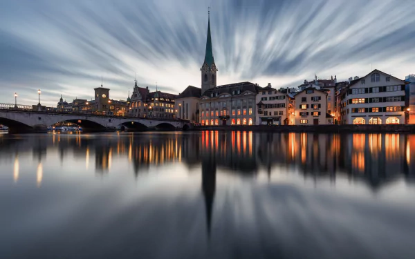 Evening view of Zurich, Switzerland, showcasing historic buildings and a church steeple reflected in the calm river, captured in a high-definition man-made cityscape.