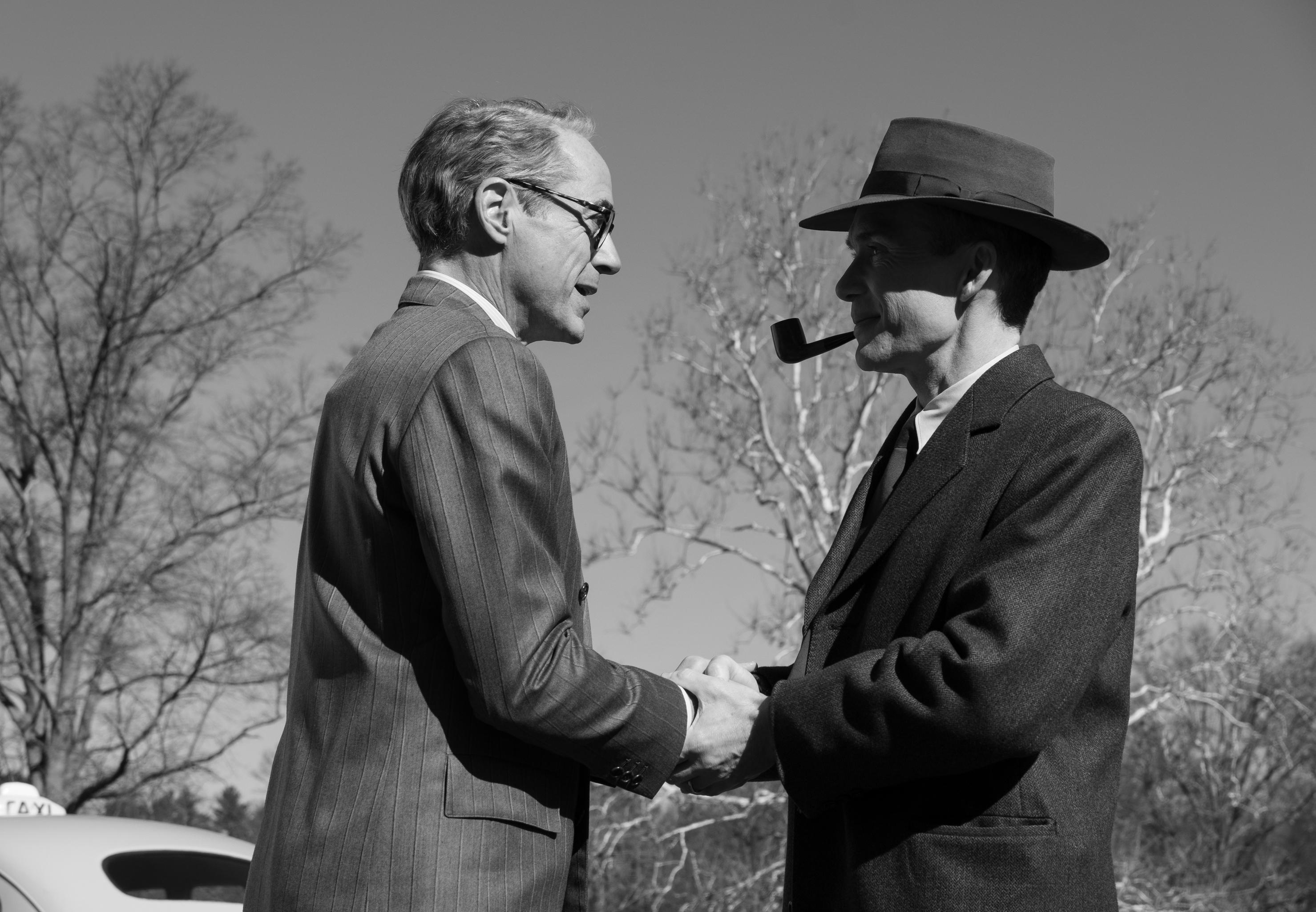 Black and white HD desktop wallpaper featuring two men in period clothing shaking hands, evoking a historical theme possibly related to the movie 'Oppenheimer'.