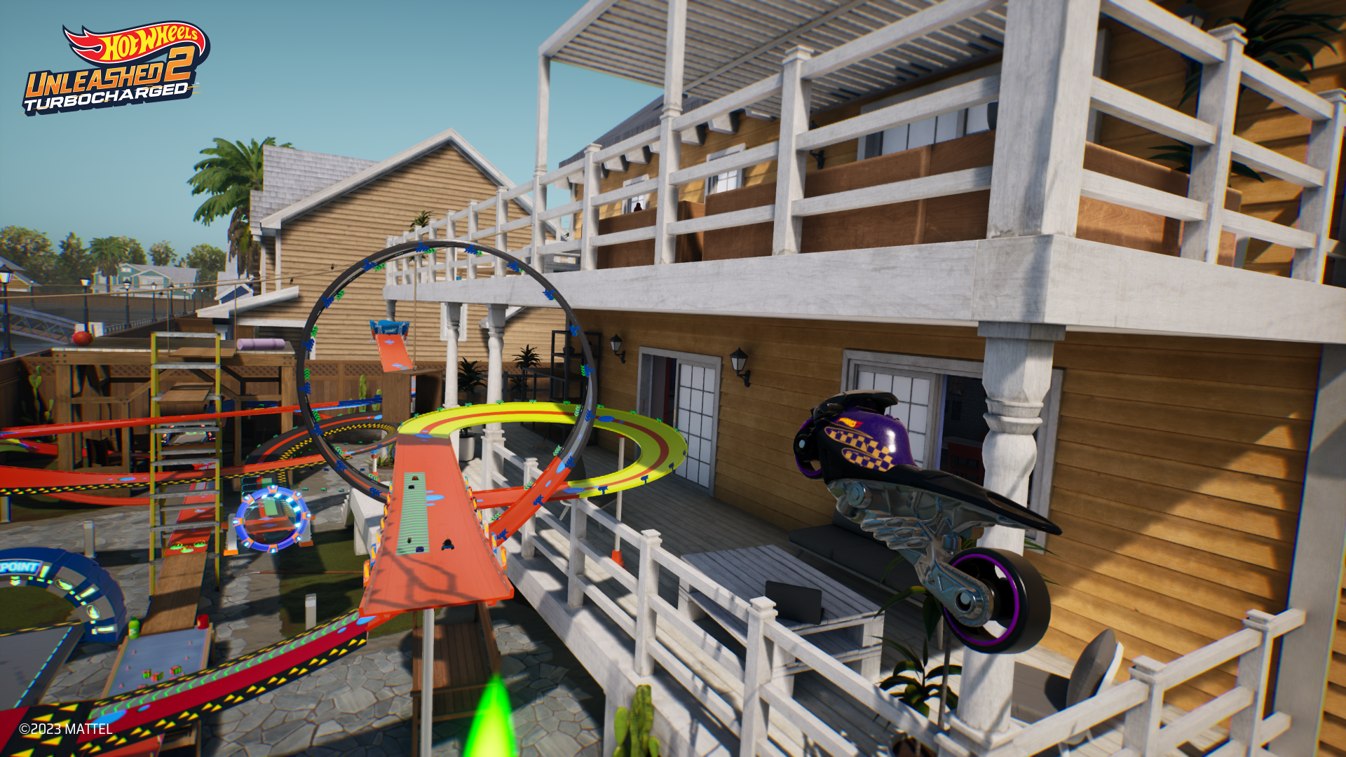 HD desktop wallpaper from Hot Wheels Unleashed 2: Turbocharged, featuring a dynamic race track scene with cars launching through loop-de-loops by a wooden house.