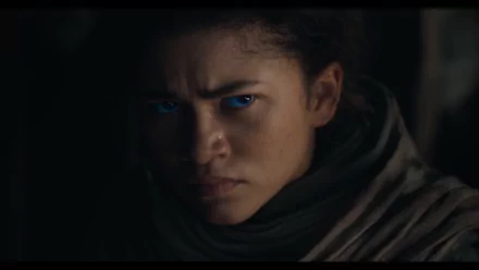 HD desktop wallpaper featuring a close-up of a character from Dune: Part Two, with intense blue eyes, wrapped in a textured cloak.
