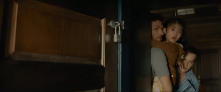 HD Desktop wallpaper featuring a suspenseful scene from Knock at the Cabin, with an adult and child peering through a partially opened door.