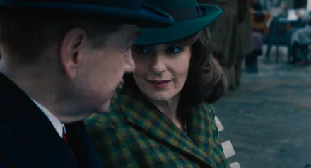 HD wallpaper featuring a scene from 'A Haunting in Venice' with a woman in a hat and plaid coat engaging in a conversation.