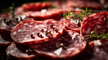 A close-up of sliced salami, garnished with herbs and spices, creating an inviting and appetizing scene. This high-definition image makes a striking desktop wallpaper.