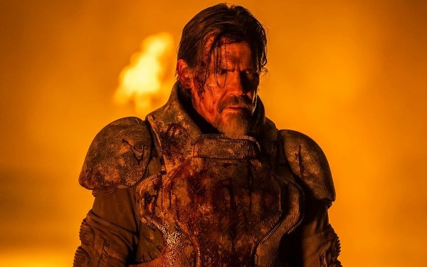 Josh Brolin as a gritty warrior in an intense scene from Dune: Part Two, in a high-definition desktop wallpaper with a dramatic orange-hued background and flame effects.